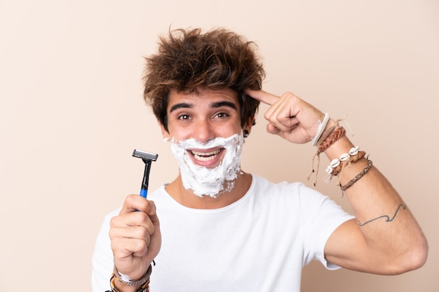 Man shaving his beard over isolated wall