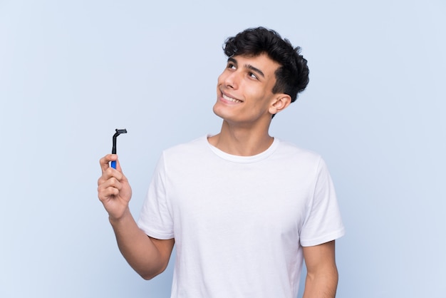 Man shaving his beard over isolated wall