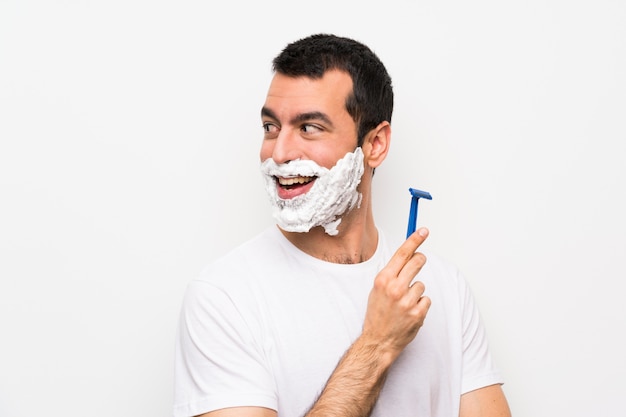 Man shaving his beard over isolated white background with arms crossed and happy