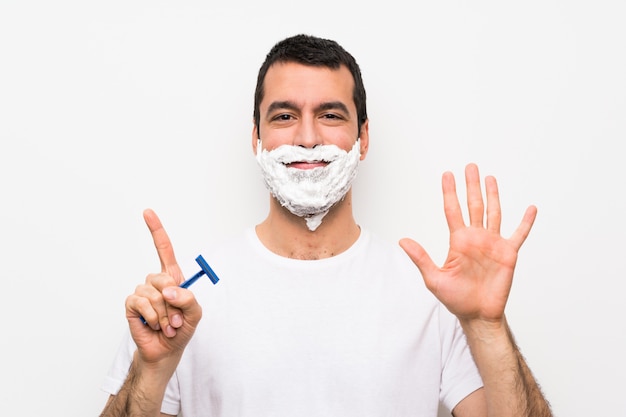 Man shaving his beard over isolated white  counting six with fingers