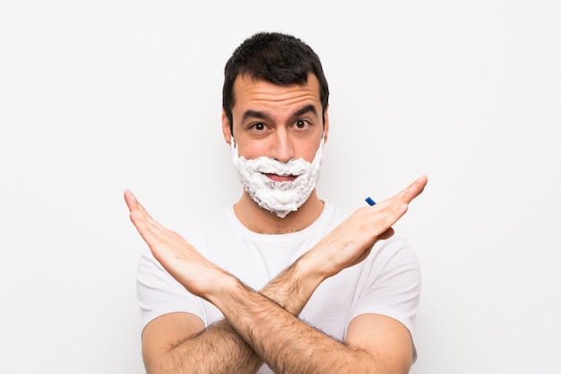 Man shaving his beard over isolated white making NO gesture