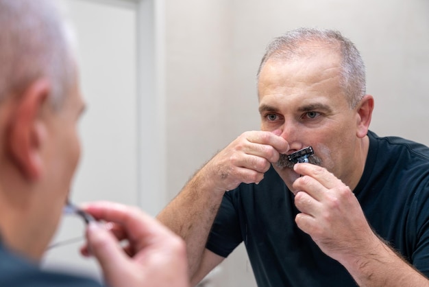 Man shaving with razor using foam in bathroom in the morning