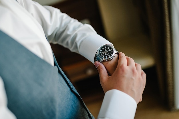 A man in a shirt adjusts the watch on his arm Close up of businessman using watch flat lay top view