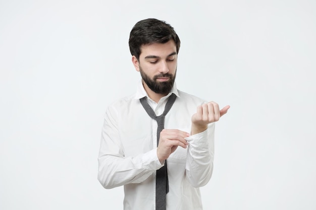 Uomo in camicia che si veste e che si aggiusta la cravatta sul collo