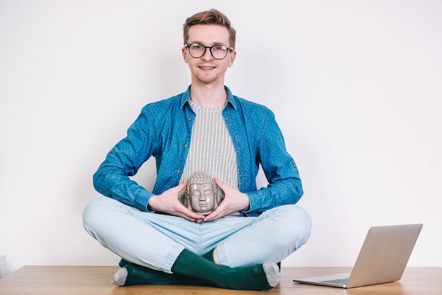 Man in shirt and glasses working on laptop computer sitting on the table on a white background