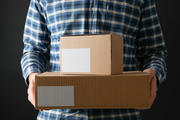 Man in shirt hold blank boxes against black background