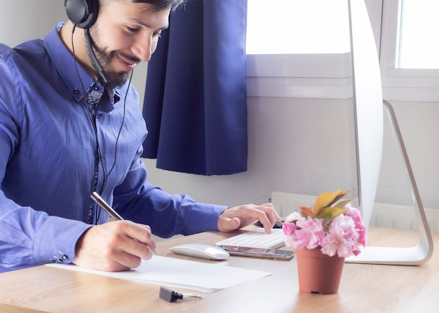 Uomo in camicia e cuffie professionali che lavorano a casa telelavoro.