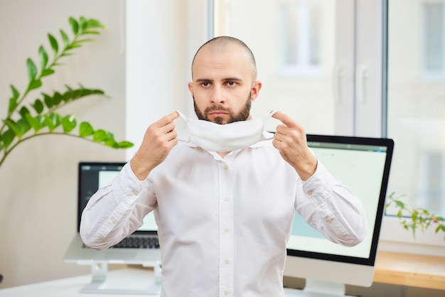 A man in a shirt putting on a face mask