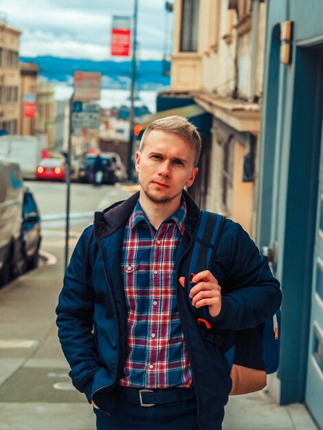 A man in a shirt walks down a street in San Francisco on a cloudy day