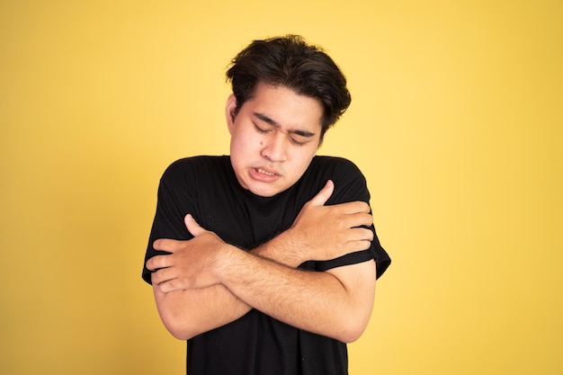 Man shivering while holding his two arms hug himself