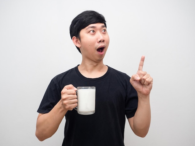 Man shocked face holding glass of milk point finger at copy space