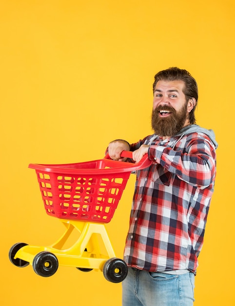 Man in shopping mall customer pushing cart buyer in supermarket empty toy trolley really busy housekeeper perfect husband need shopping list bearded man go shopping with empty shopping cart