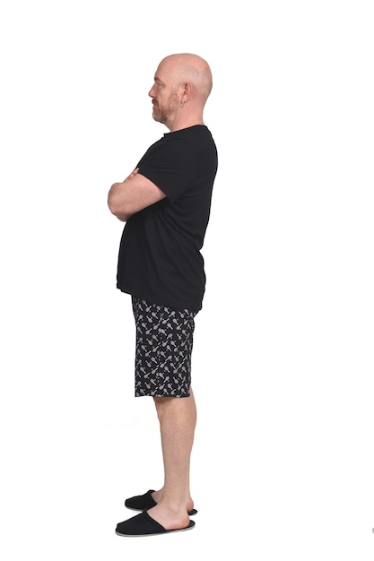 Man in short pant pajamas on white background, arms crossed, profile