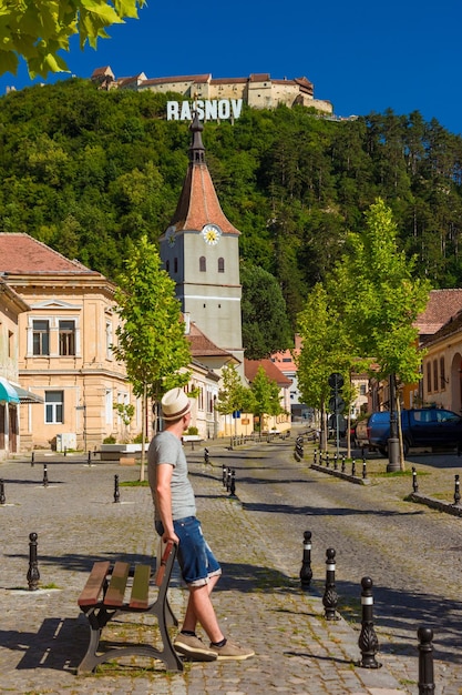 Rasnov のベンチに座っているショート パンツと帽子の男