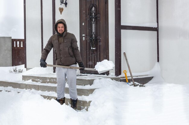 家の階段から雪かきをする男