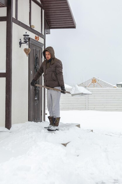 家の階段から雪かきをする男