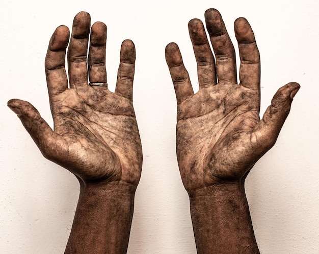 남자는 흰색 배경에 격리된 손바닥으로 더러운 손을 보여줍니다.
