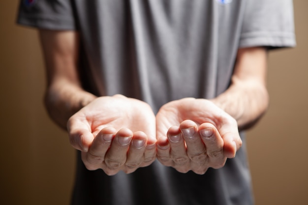 写真 茶色の背景に空の手のひらを示す男