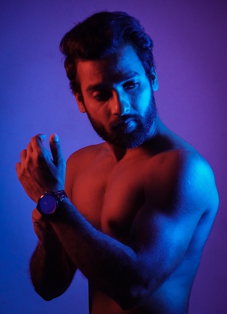 Man showing his watch with his his physic in neon light