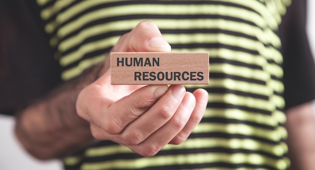 Man showing Human Resources text on wooden block.