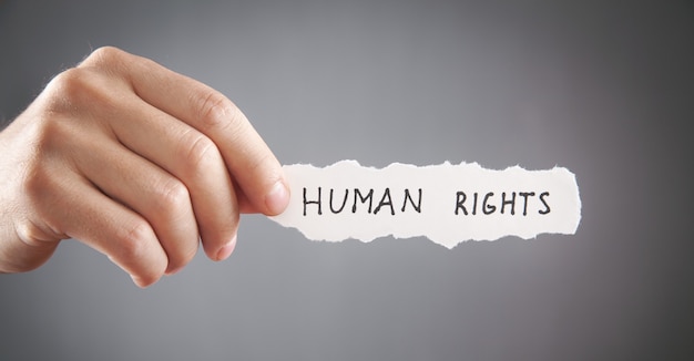 Man showing Human Rights text on torn paper.