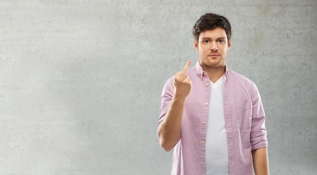 Photo man showing middle finger over grey concrete wall