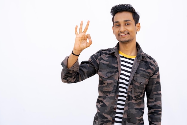 Man showing Okay Gesture with hands and smiling wearing white and black clothes