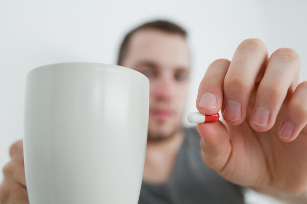 Man showing a pill and and a mug