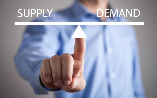 Man showing supply and demand word balance scales Business concept