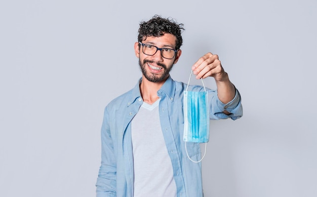 Man showing surgical mask Young handsome man offering surgical mask on isolated background