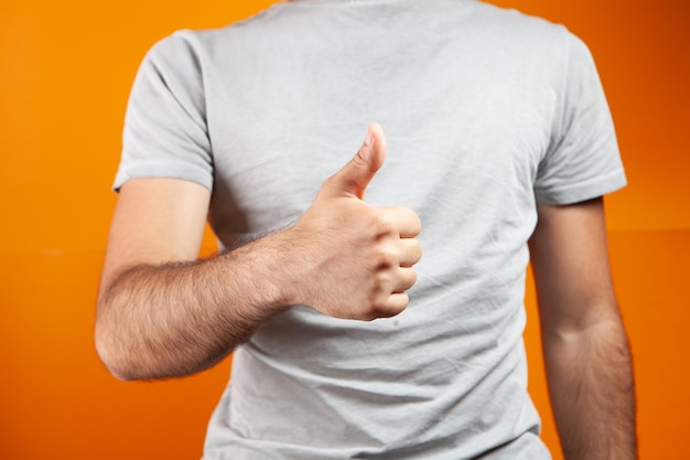 Man showing thumb up on orange background