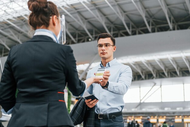 Man showing vaccination certificate young businessman in formal\
clothes is in the airport at daytime