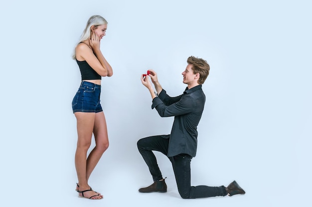 Photo man showing wedding ring to shocked woman while standing against white background