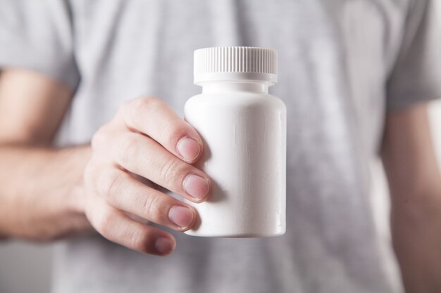 Man showing white bottle of pills.