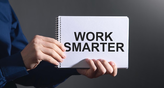 Человек, показывающий текст Work Smarter в блокноте