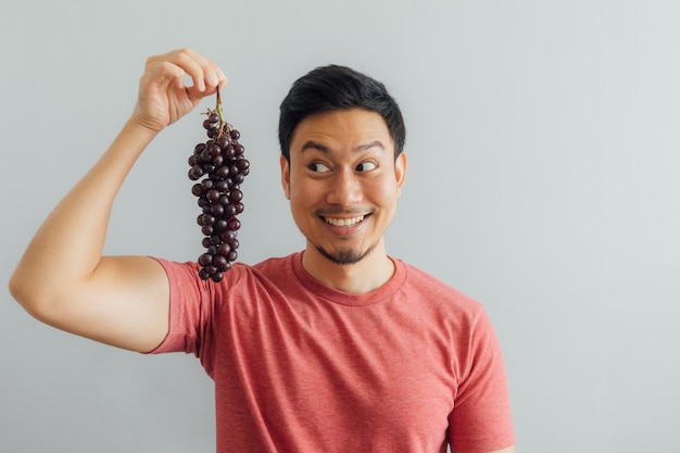 Man shows bunch of red grapes.