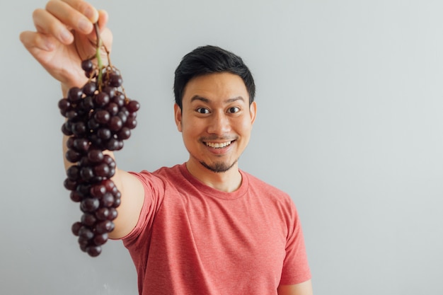 Man shows bunch of red grapes.