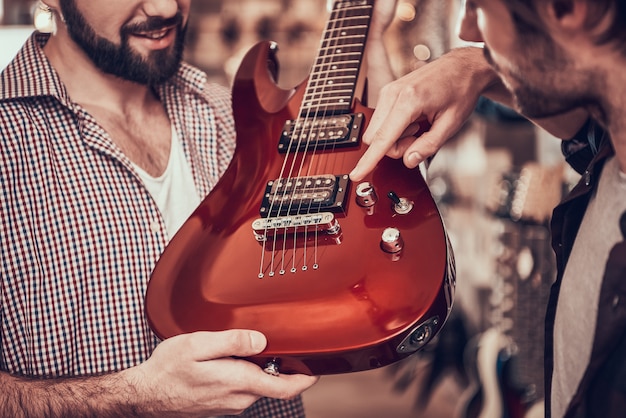 Man shows for buyer where guitar volume control.