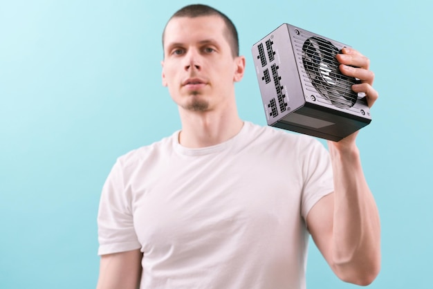 A man shows a computer power supply in front of his face on a blue background Electronic Supply Communication Component Connection Down Gesture Hardware Human Negative Unit Electric