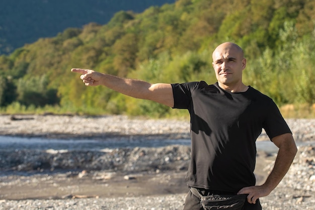 a man shows a hand sign on the background of nature in the mountains