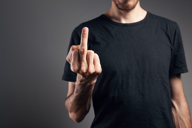 Man shows middle finger on gray background