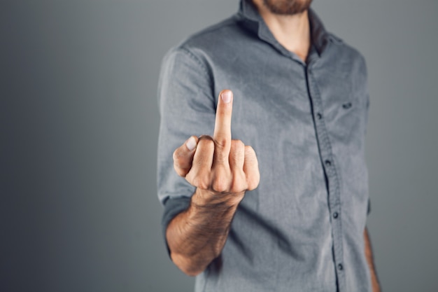 Man shows middle finger on gray background