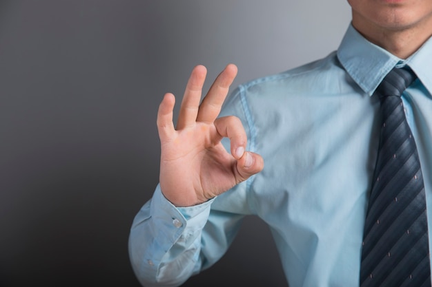 Man shows ok on gray wall