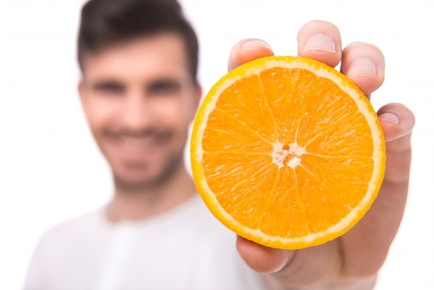 A man shows an orange in his hand.