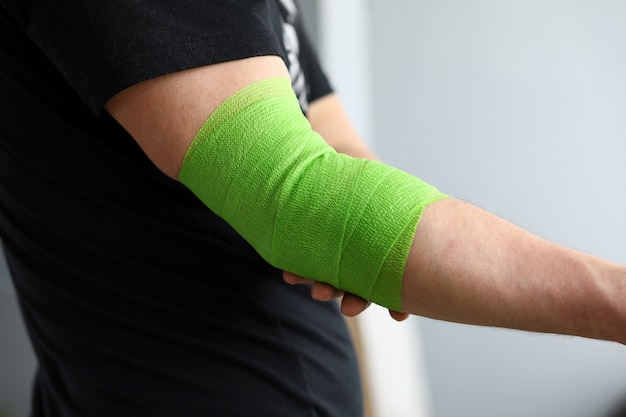 Man shows stretching on arm with elastic bandage.