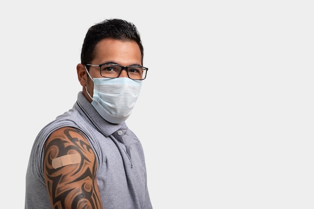 мужчина показывает, что он был вакцинирован, указывает на повязку на руке, в маске, фото