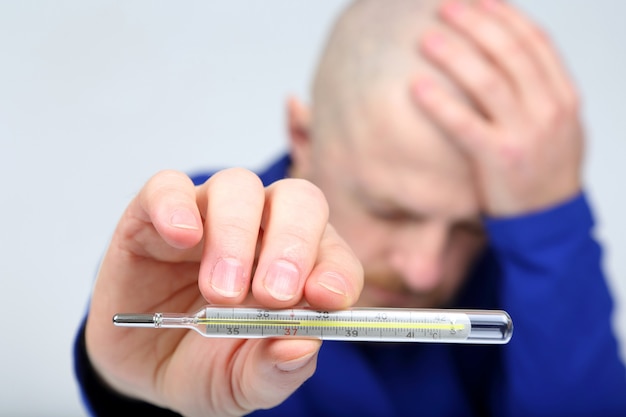 Man shows a thermometer with a high temperature