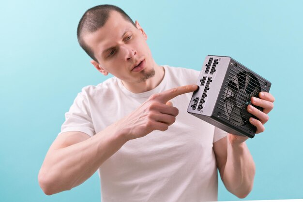 A man shows with a pointing finger at a pin sockets of a computer power supply on a blue background Hand Electricity Electronic Supply Component Connection Unit Electric Pinouts Plugs