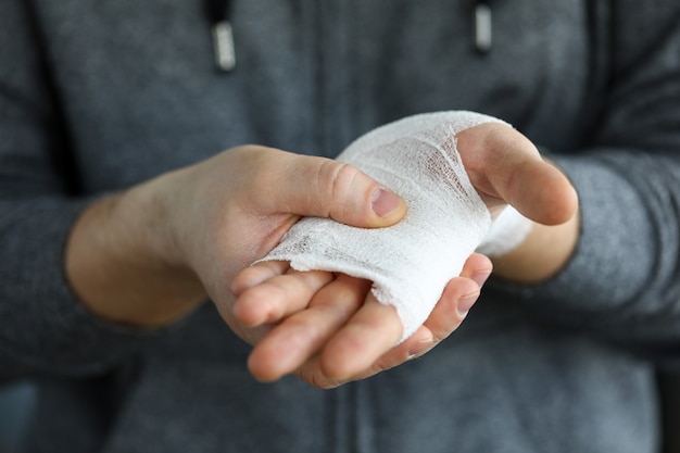 Man shows wounded arm rewound with white bandage