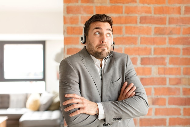 Man shrugging, feeling confused and uncertain, doubting with arms crossed and puzzled look